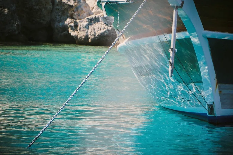 Ankerkette läuft vom Bug einer Yacht in türkisfarbenes Wasser