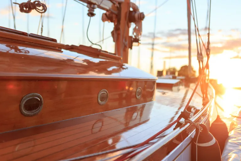 Lackiertes Holzdeck einer Segelyacht im Hafen bei tief stehender Sonne
